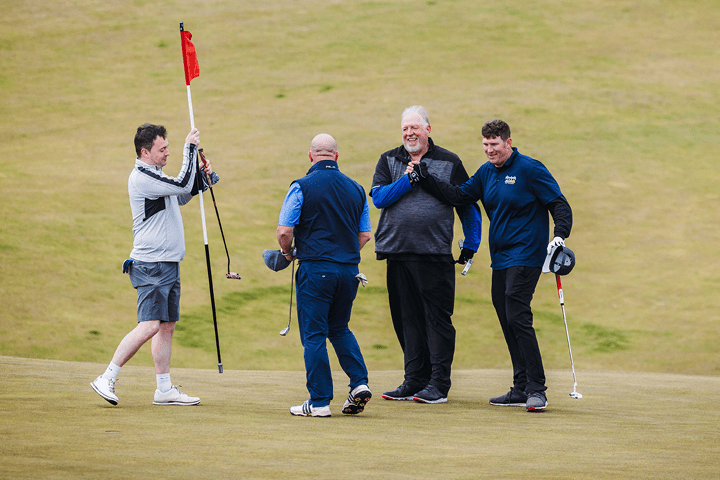 The Experience Golf Father and Son Tournament guests celebrating on the 18th green at Kingsbarns Golf Links