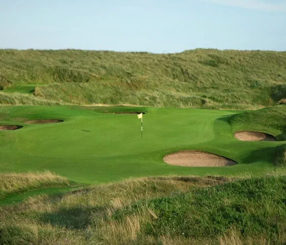 The golf course and putting green with the flagsticks adn holes at Royal Aberdeen Golf Course in Aberdeen in Scotland surrounded by green hills 