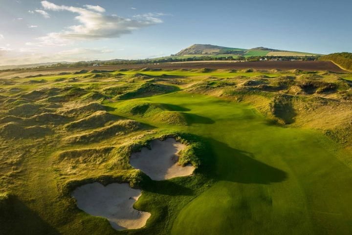 The bunkers on the golf course with the sun shining over at the Dumbarnie Links golf course at St Andrews in Scotland