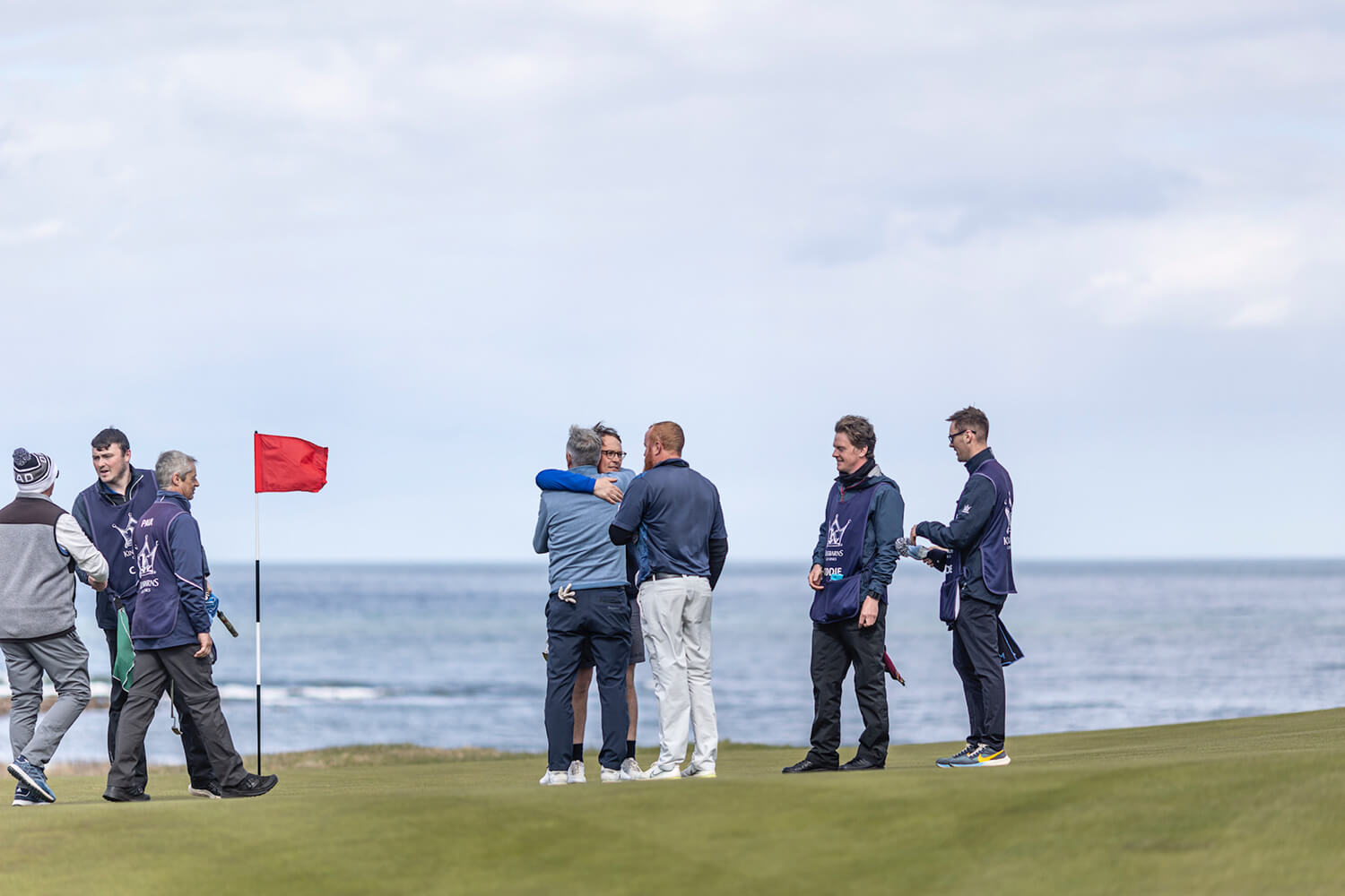 A group of golfers hugging and chatting on the course for the annual Father and Son tournament at St Andrews in Scotland