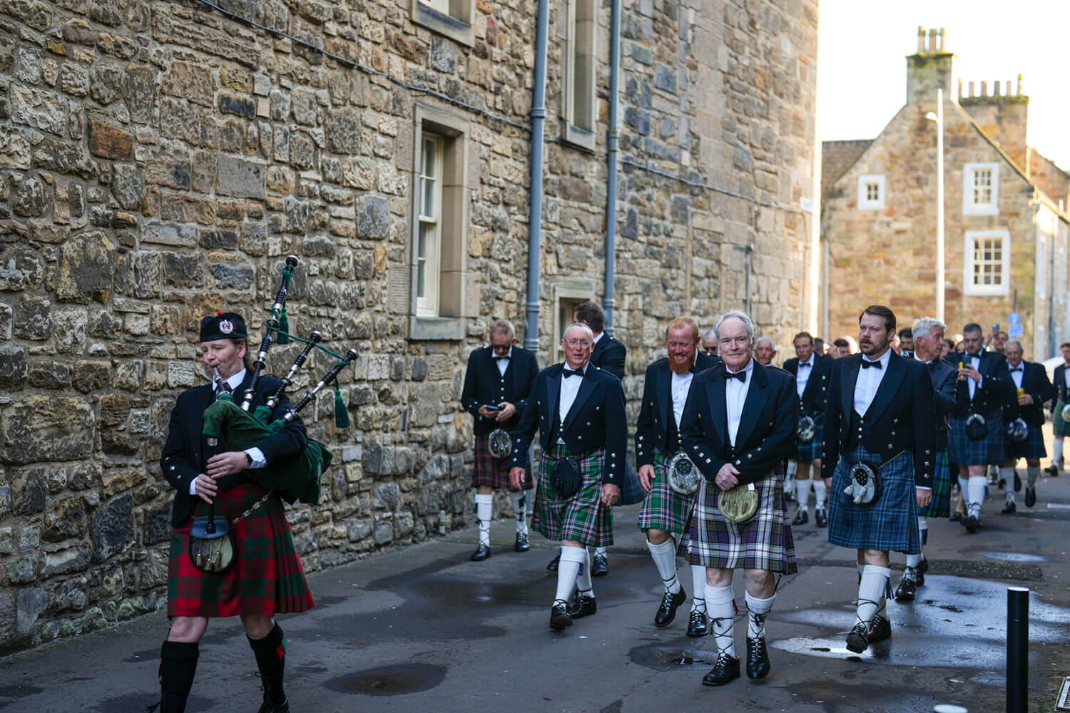 Participants of the Father and Son golf tournament walking down the street in St Andrews town dressed in kilts to celebrate their final celebration dinner and awards